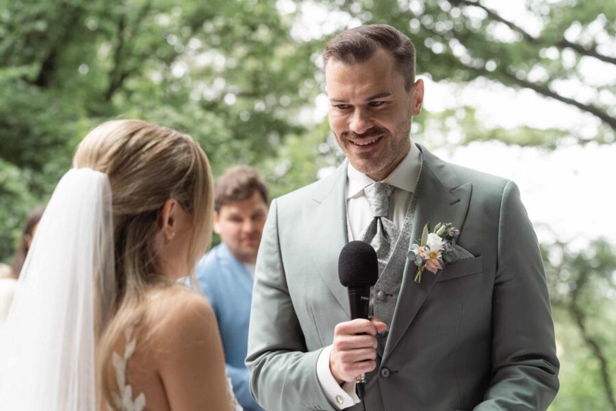 Bräutigam spricht in Mikrofon während Trauung draußen