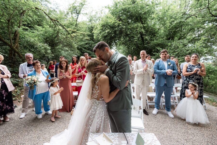 Brautpaar küsst sich im Freien vor applaudierenden Gästen