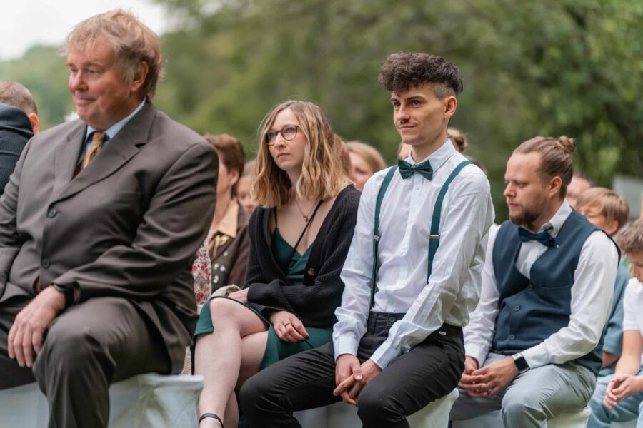 Hochzeitsgäste sitzen im Freien während Zeremonie