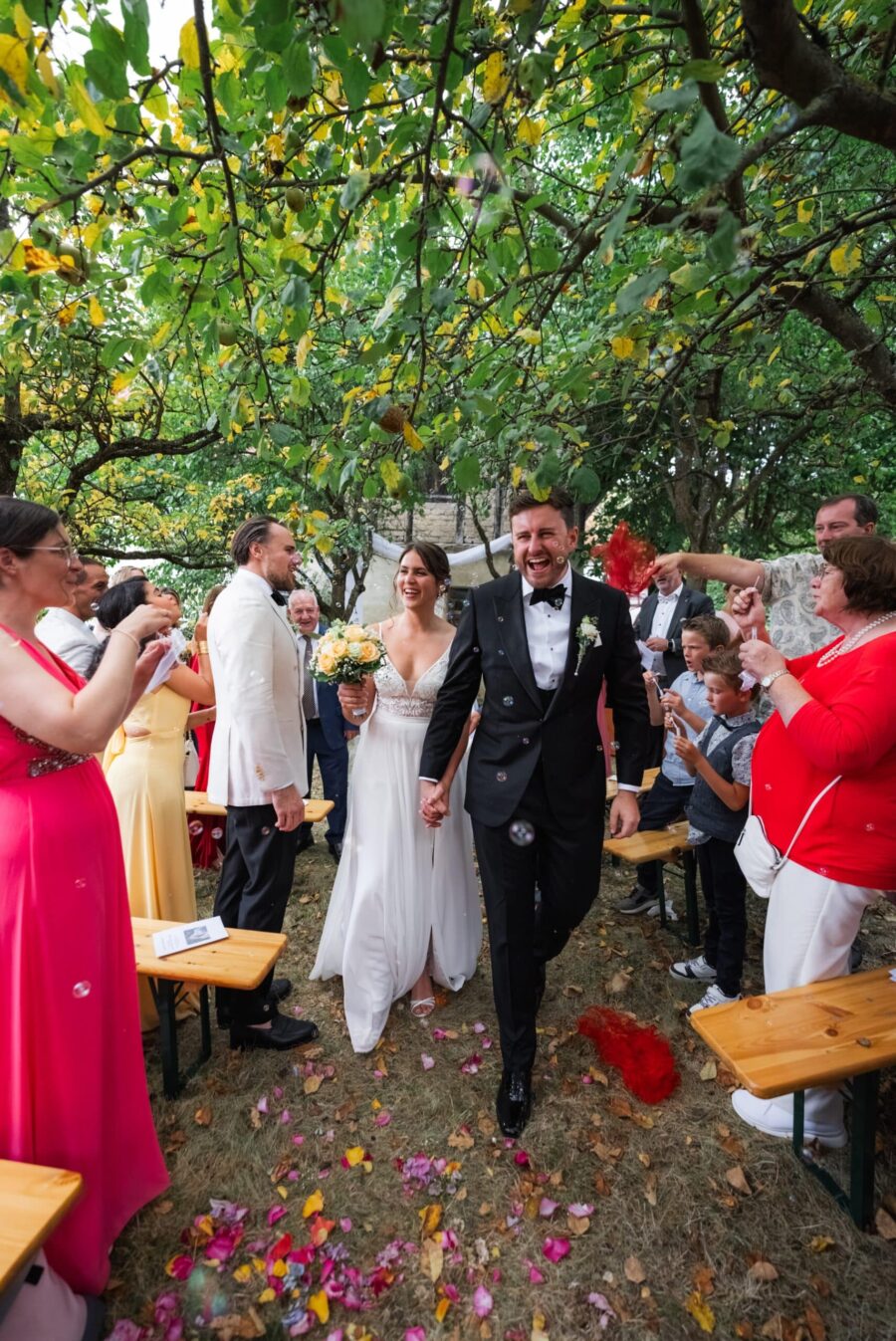 Brautpaar Hand in Hand im Garten mit Gästen