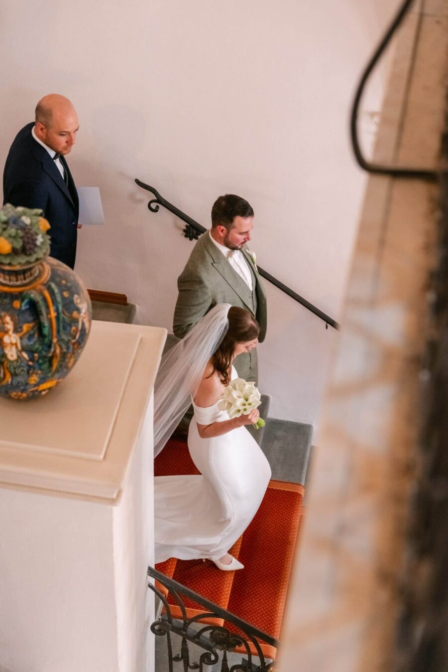 Braut mit Brautstrauß und Bräutigam auf Treppe innen
