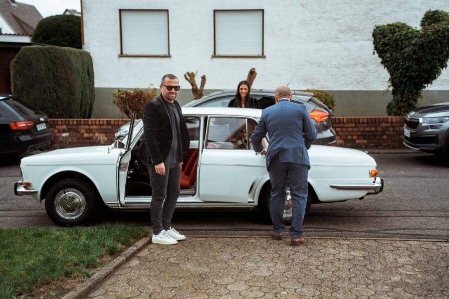 Gäste steigen in Hochzeitsauto ein.