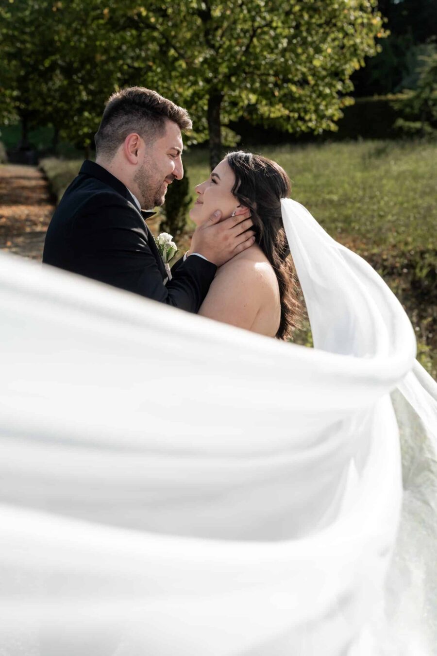 Brautpaar im Garten mit wehendem Schleier