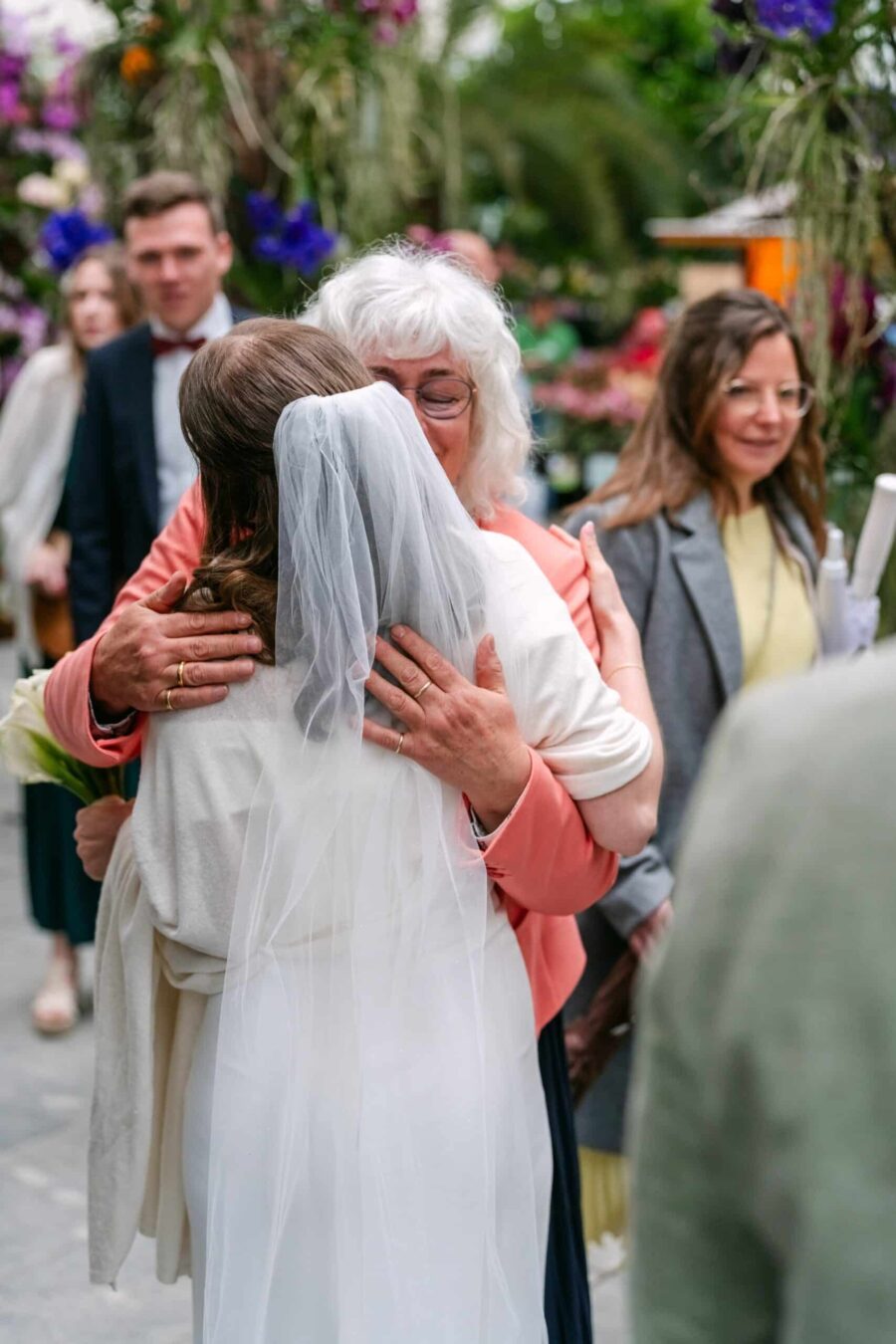 Braut umarmt Gratulantin im blühenden Garten