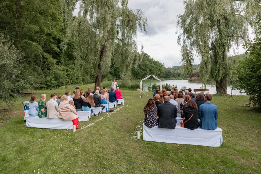 Outdoor-Trauung am See mit Gästen und Zeremonienleiter