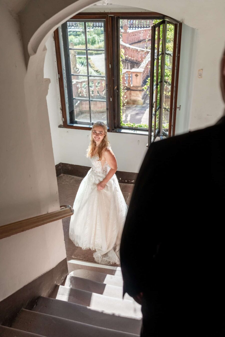 Braut auf Treppe mit offenem Fenster im Schloss.