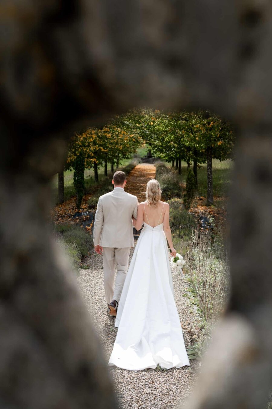 Brautpaar spaziert im herbstlichen Gartenweg