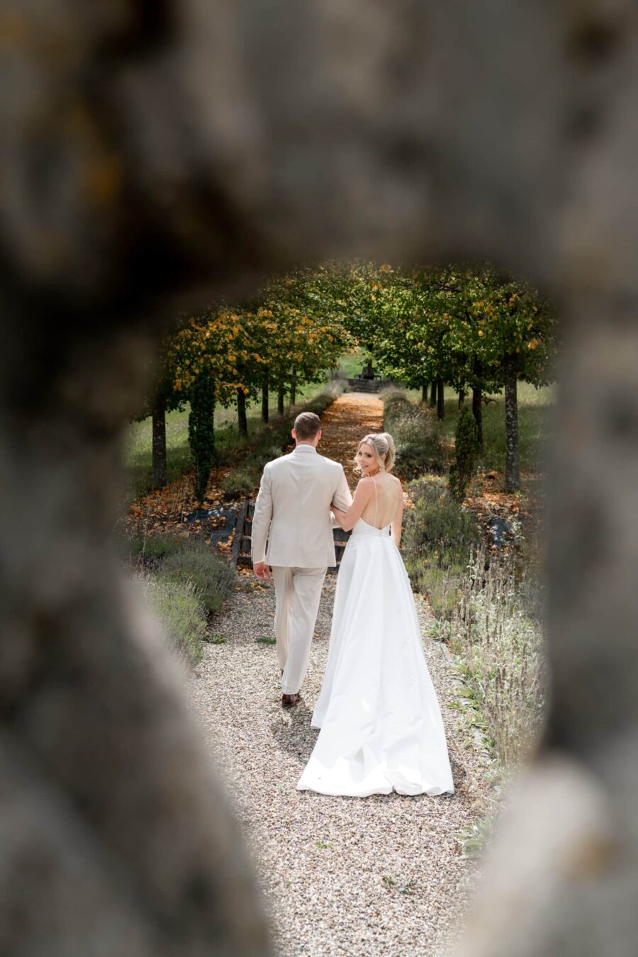 Brautpaar spaziert durch herbstlichen Gartenweg