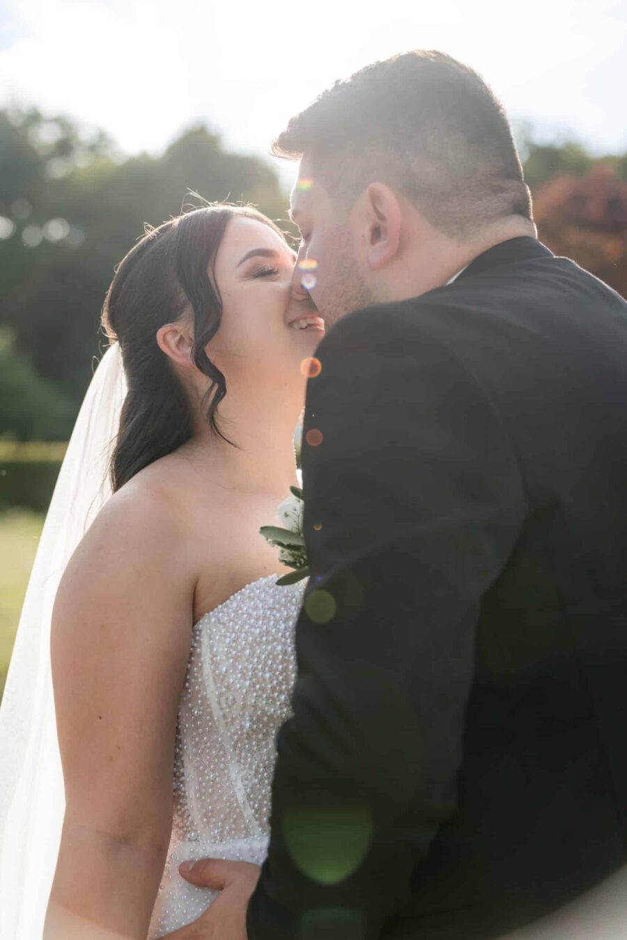 Brautpaar küsst sich im Sonnenlicht im Garten
