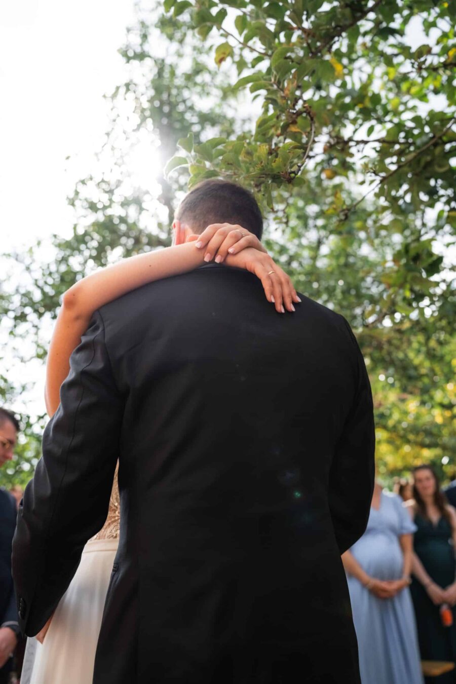 Brautpaar umarmt sich im sonnigen Garten