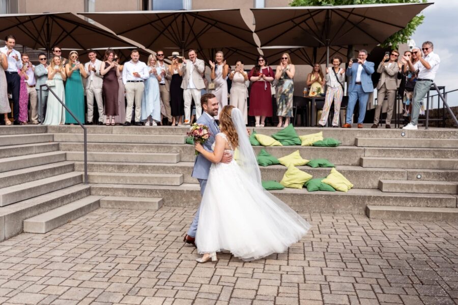 Brautpaar tanzt vor applaudierenden Gästen draußen