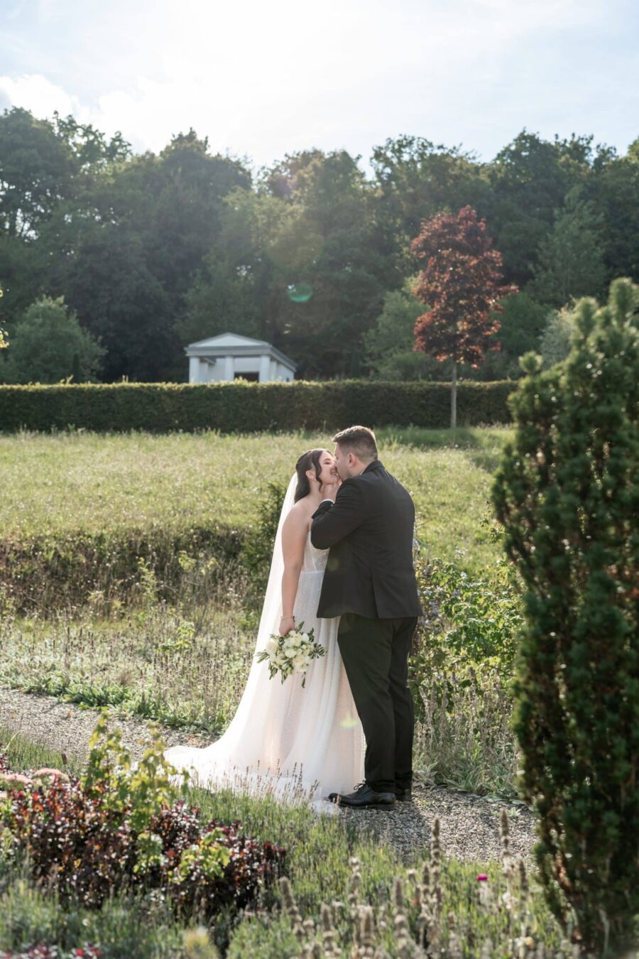 Brautpaar küsst sich im sonnigen Garten