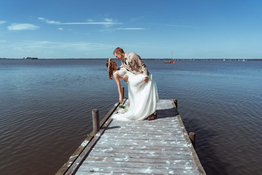 Brautpaar umarmt sich auf Steg am See.