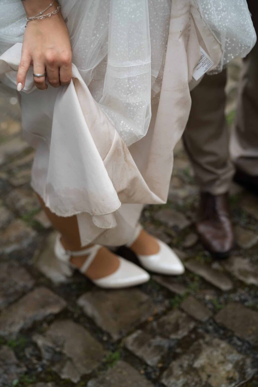 Schmutziger Hochzeitskleid-Saum auf Kopfsteinpflaster.