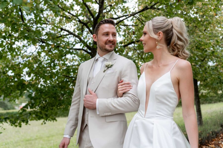 Brautpaar spaziert im grünen Garten.