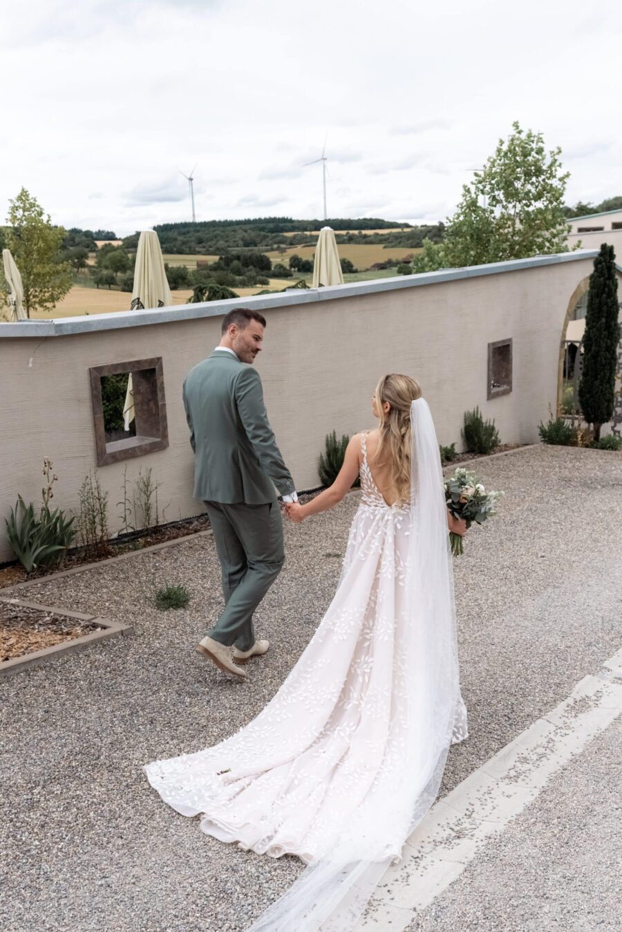 Brautpaar spaziert durch Garten mit Windrädern