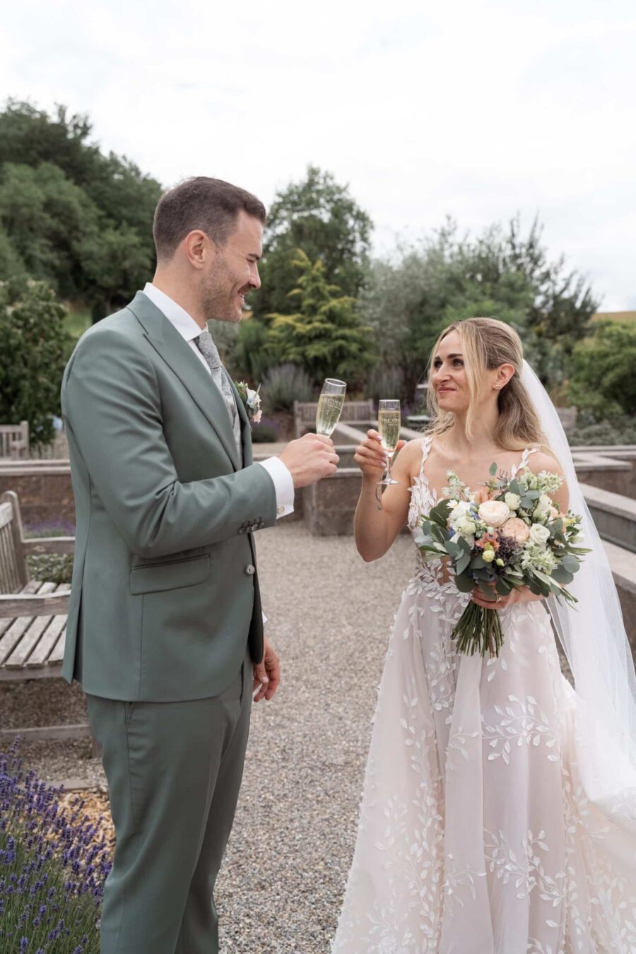 Brautpaar stößt mit Champagner an im Garten.