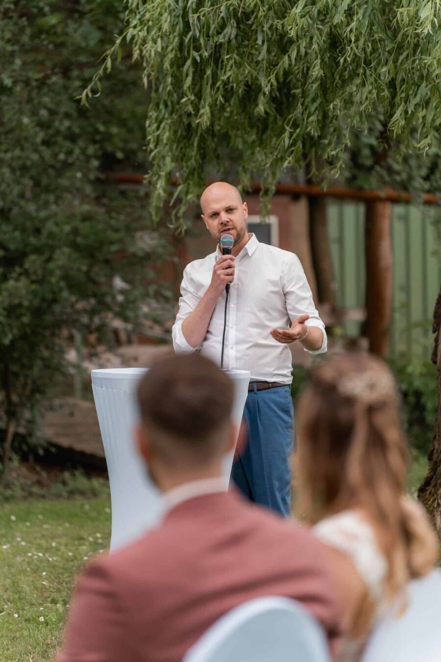 Redner hält Hochzeitsrede im Garten.