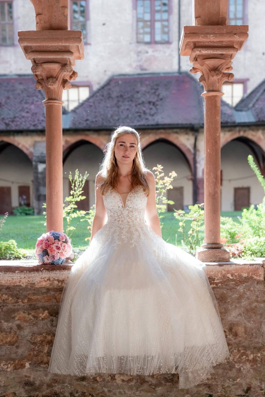 Braut in Spitzenkleid im historischen Innenhof