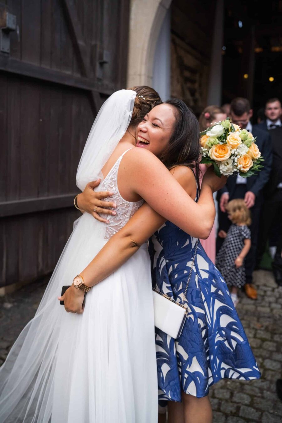 Braut und Gast umarmen sich freudig bei Hochzeitsempfang