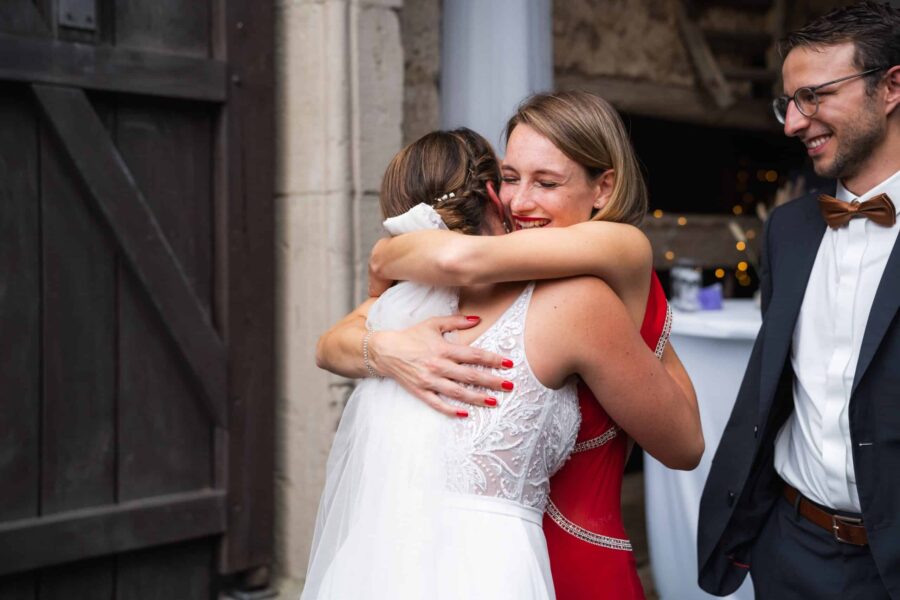 Braut umarmt Hochzeitsgast in Festsaal.