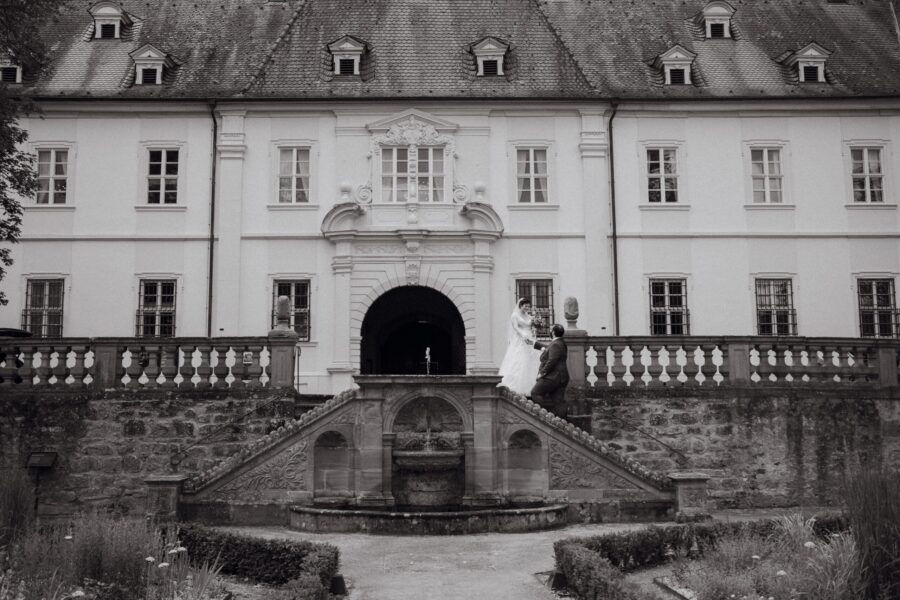 Brautpaar auf Schlosstreppe vor historischer Fassade