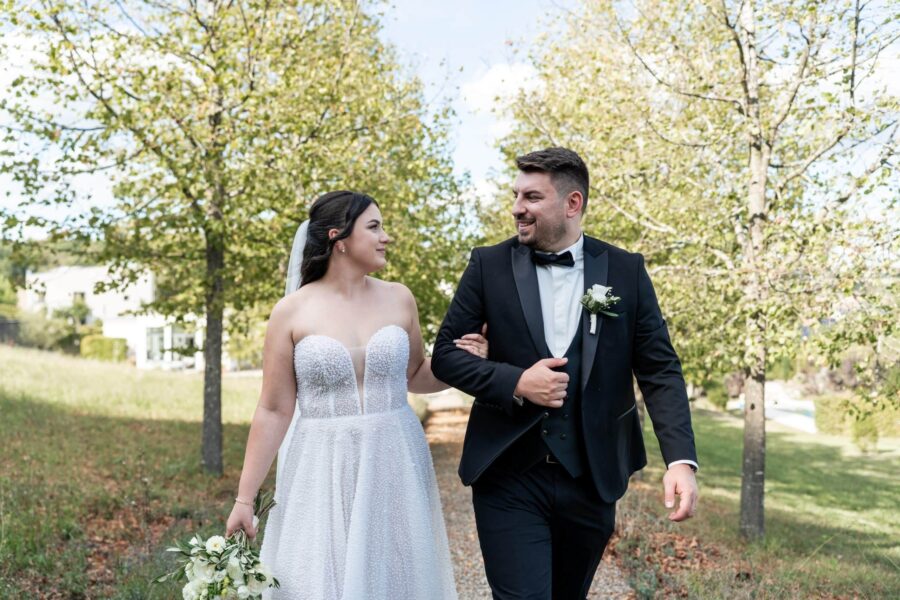 Brautpaar spaziert im grünen Gartenumfeld