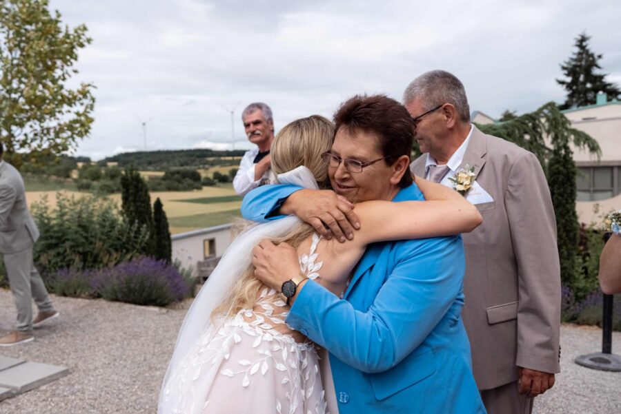 Brautpaar umarmt Gäste im Freien bei Hochzeit