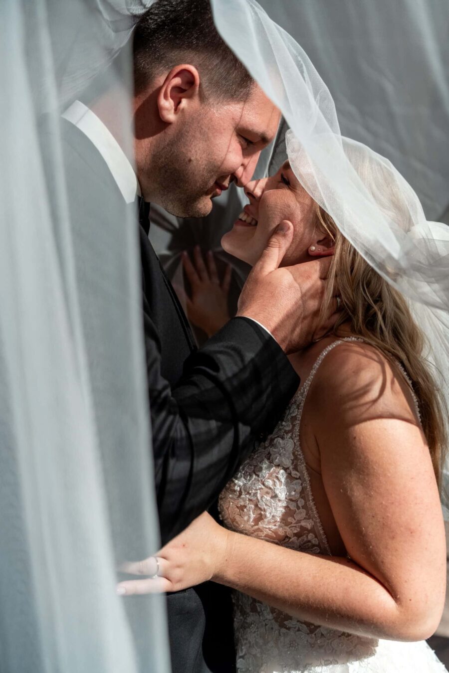 Brautpaar unter Brautschleier lächelt verliebt