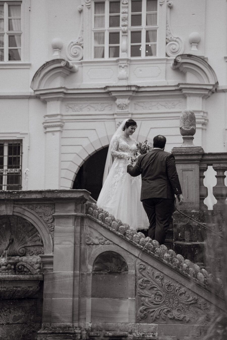 Brautpaar auf Treppe vor historischer Kulisse