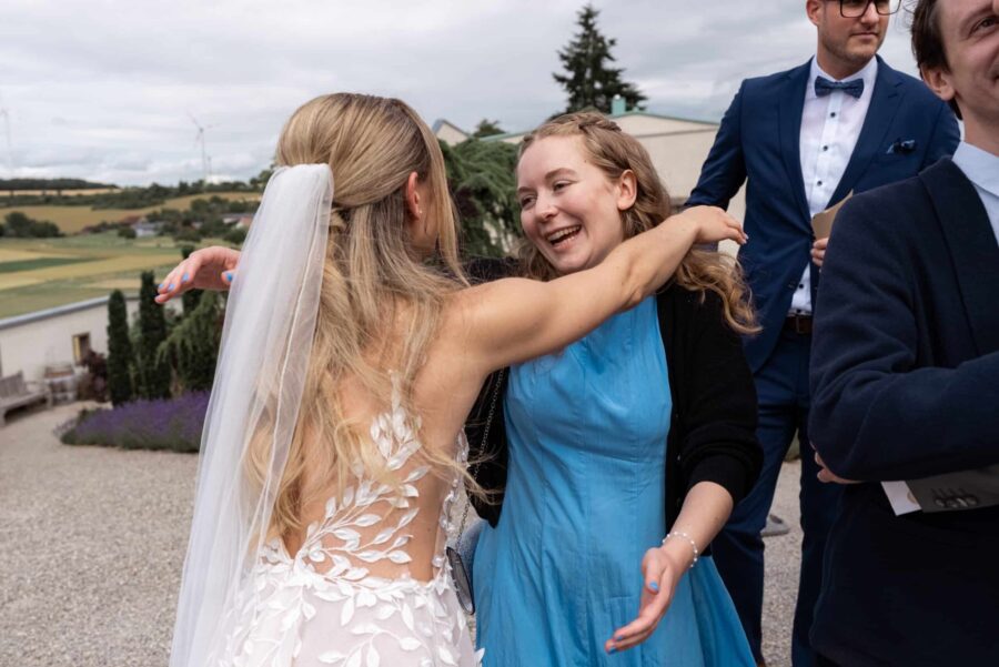 Braut umarmt Gast bei Feier im Freien