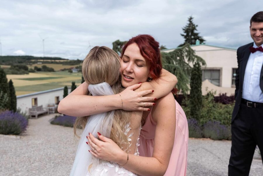 Umarmung bei Hochzeit im Garten mit Landschaftshintergrund