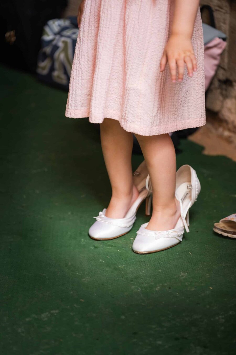 Kind im Hochzeitskleid trägt große Pumps