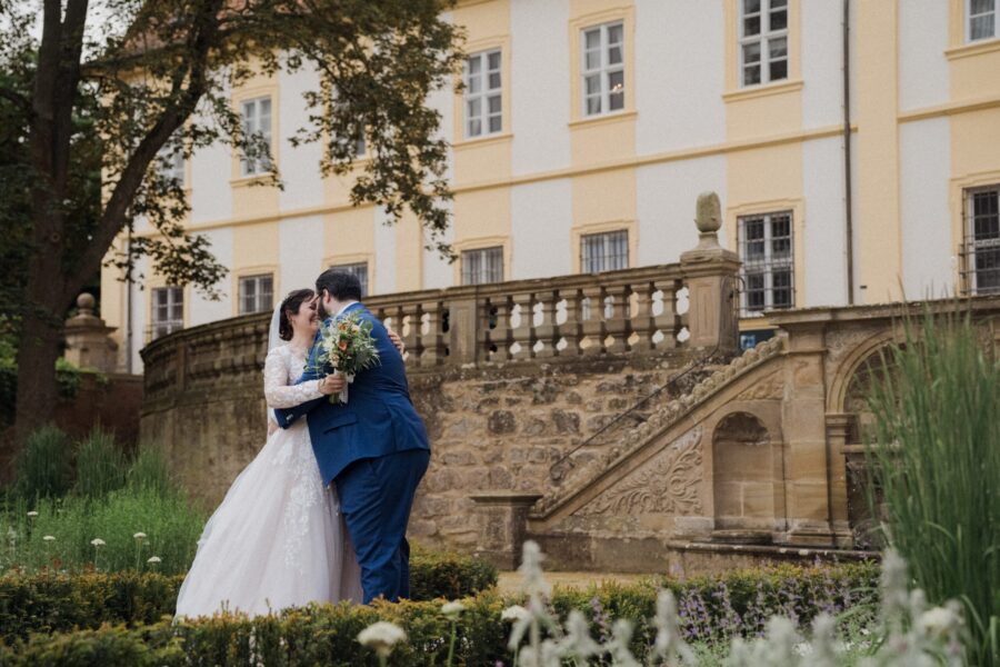 Brautpaar küsst sich vor historischem Gebäude