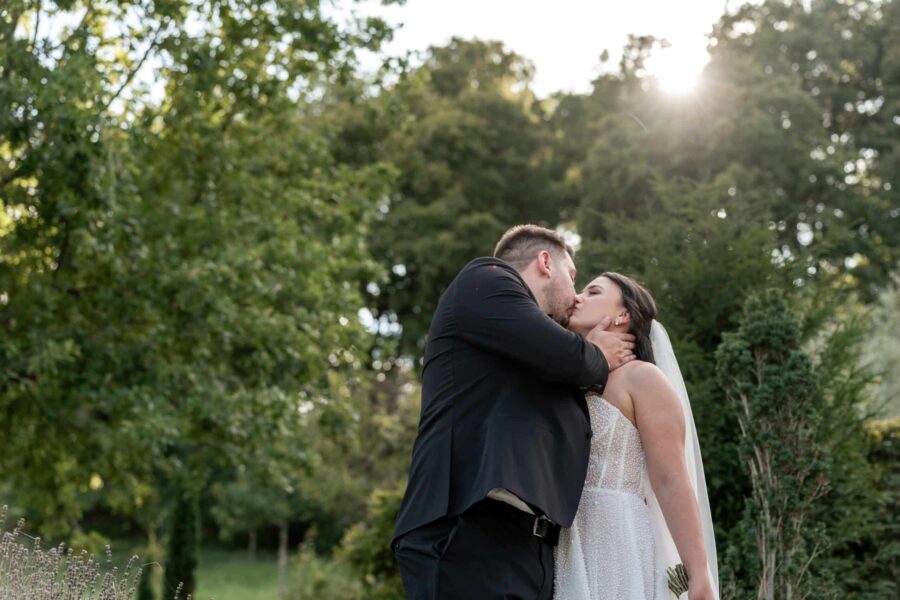 Brautpaar küsst sich im sonnigen Garten
