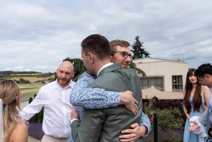 Gäste umarmen sich bei Hochzeit im Freien
