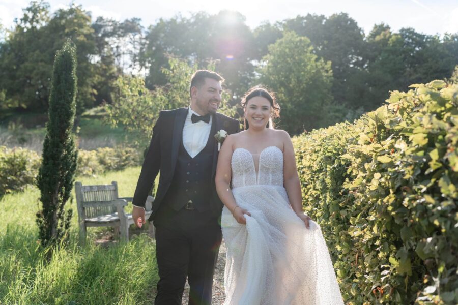 Brautpaar spaziert im sommerlichen Garten