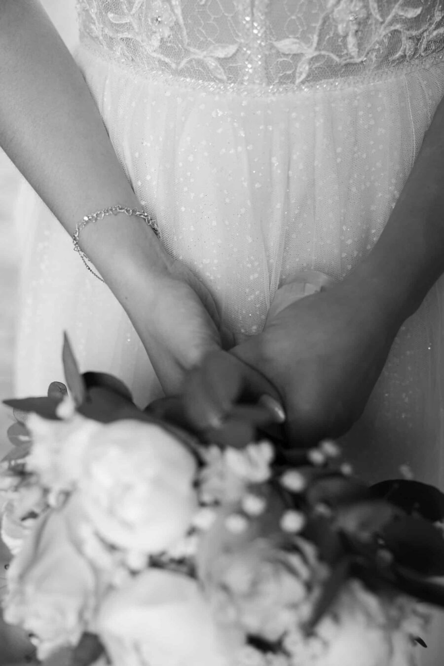 Brautkleid-Handdetail mit Blumenstrauß