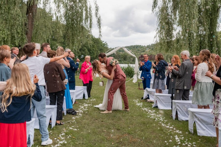 Brautpaar küsst sich im Garten vor Hochzeitsgästen