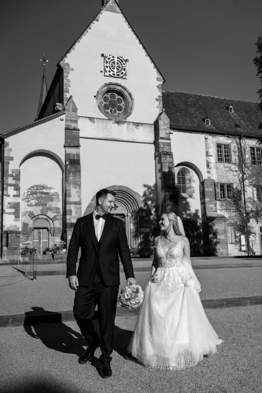 Brautpaar vor historischer Kirche bei Sonnenschein