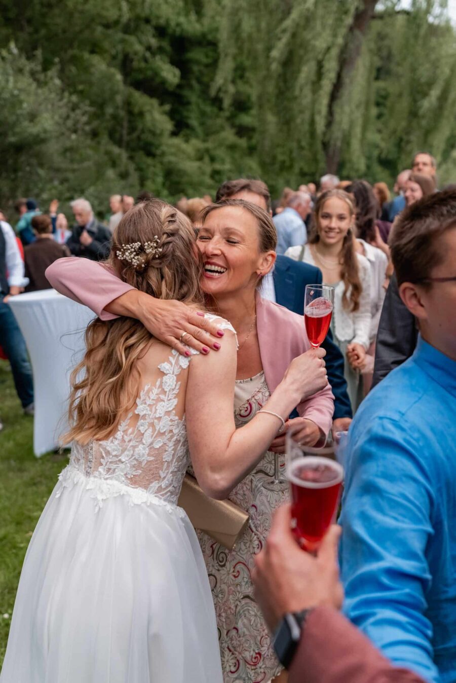 Hochzeitsumarmung im Garten mit Gästen