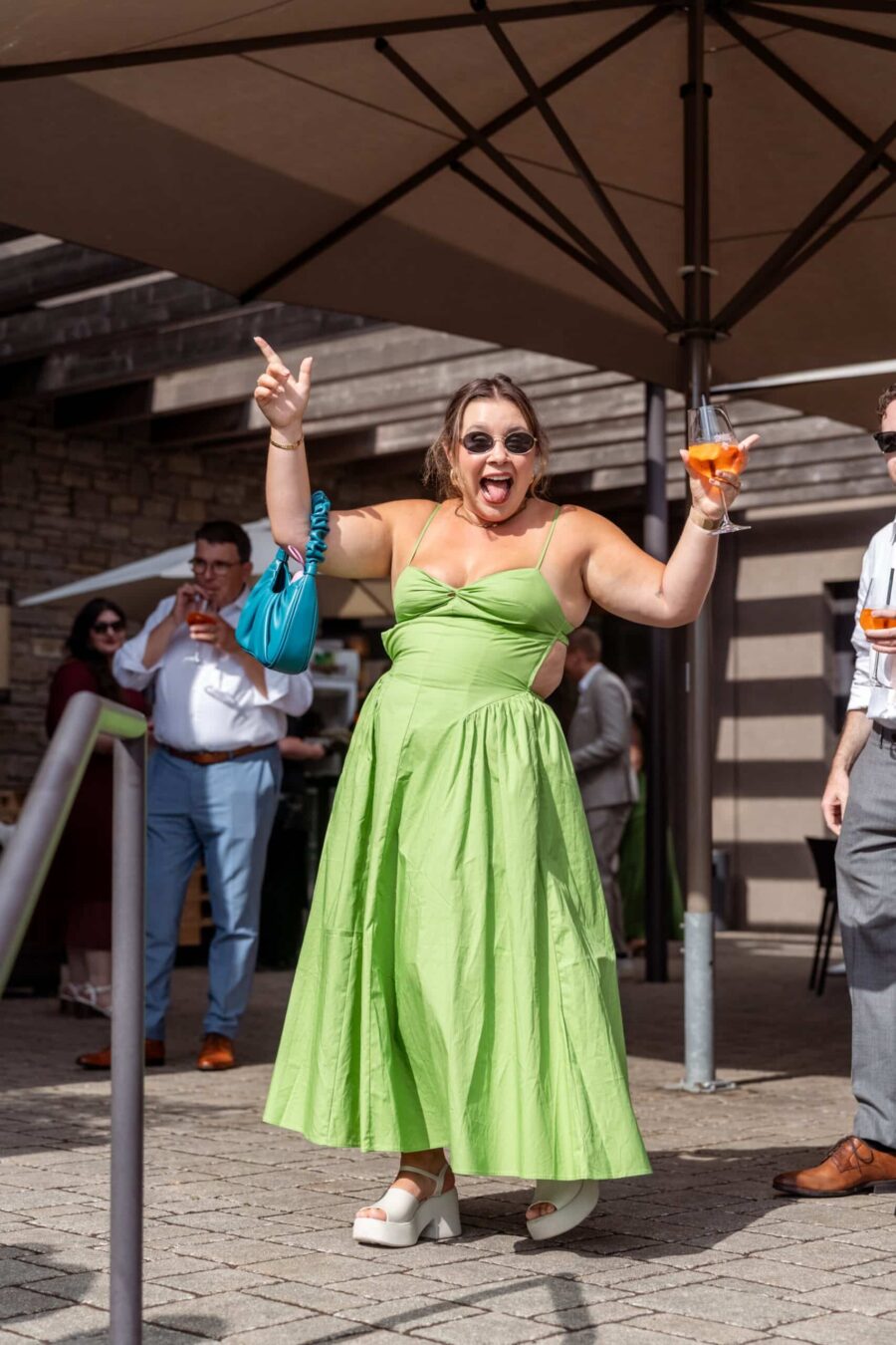 Fröhliche Hochzeitsgäste unter Sonnenschirm feiern.