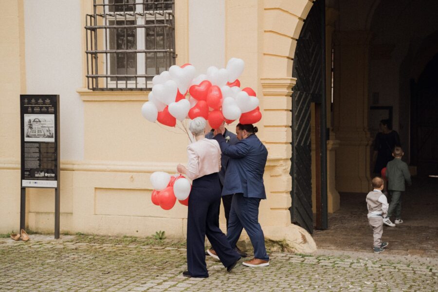 Gäste mit Herzluftballons vor historischem Gebäude