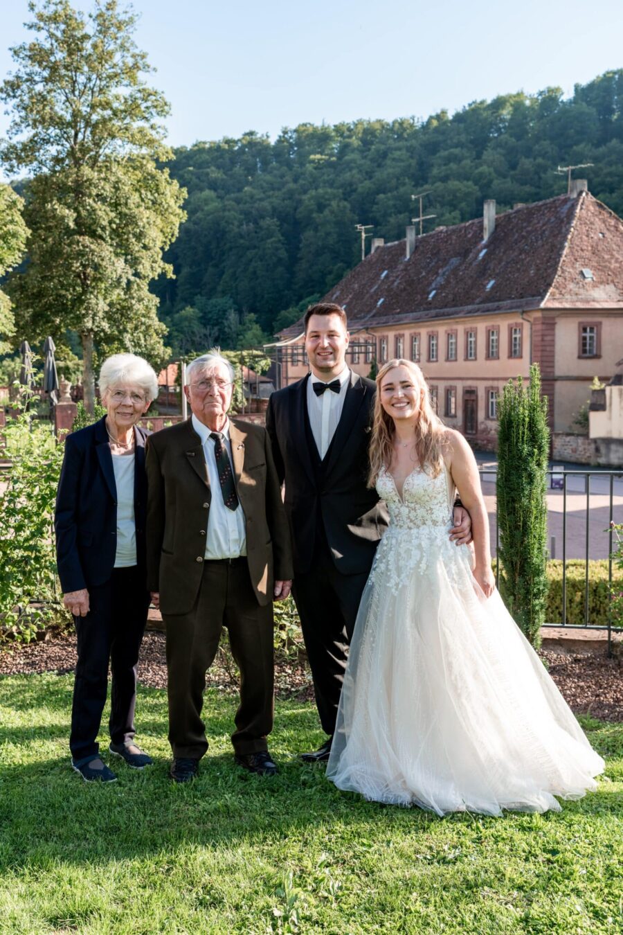 Brautpaar mit Gästen im Garten vor historischem Gebäude