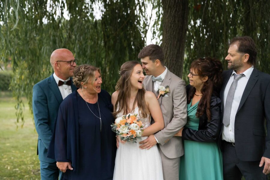 Brautpaar mit Familie unter grünem Baum
