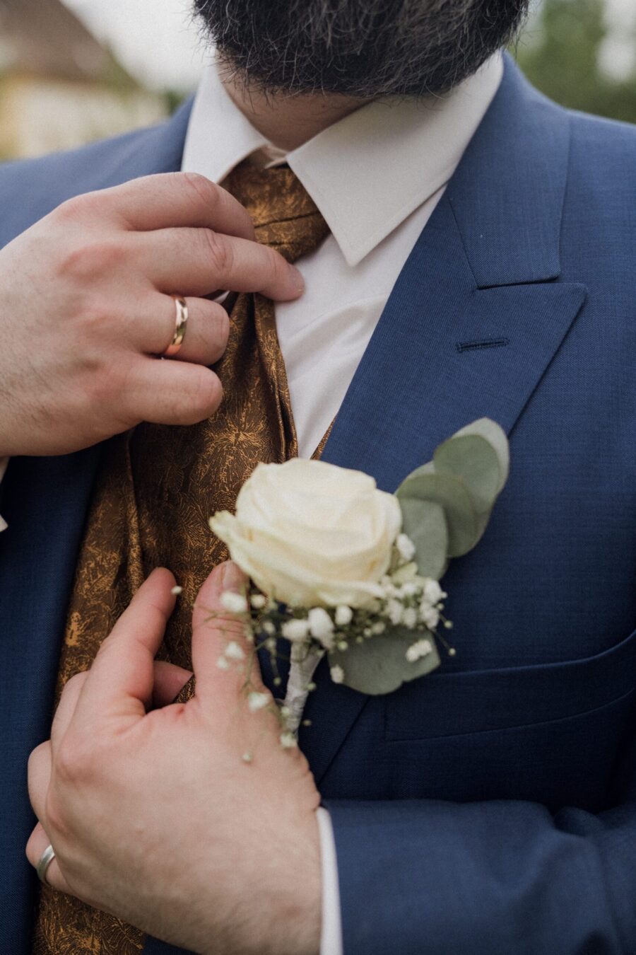Anzug mit Krawatte und weißer Blumenanstecknadel
