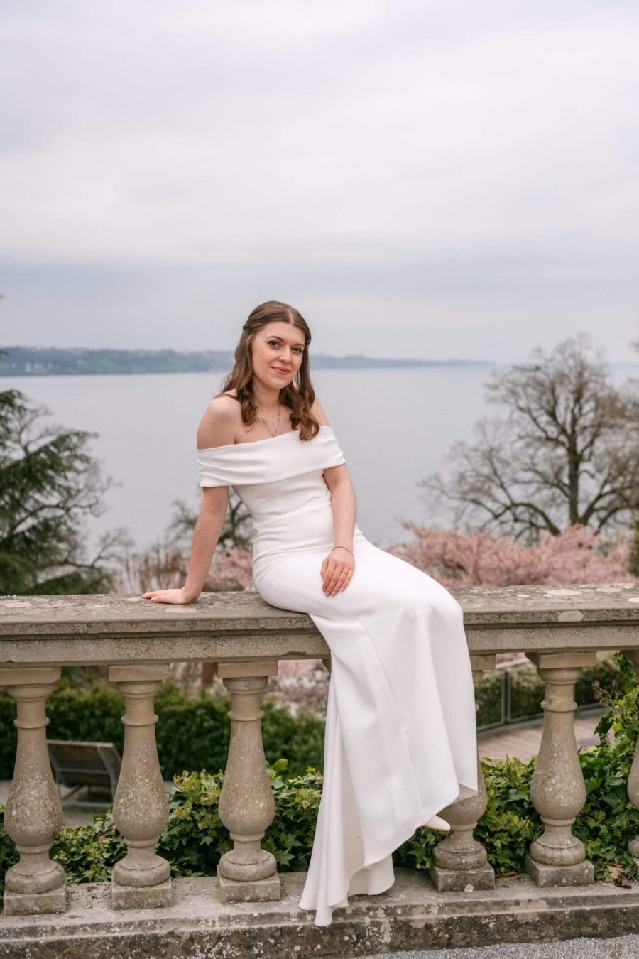 Hochzeit Insel Mainau Bodensee – Heiraten am Bodensee 233 Braut auf Steinbalustrade mit Seeblick im Frühlingsgarten