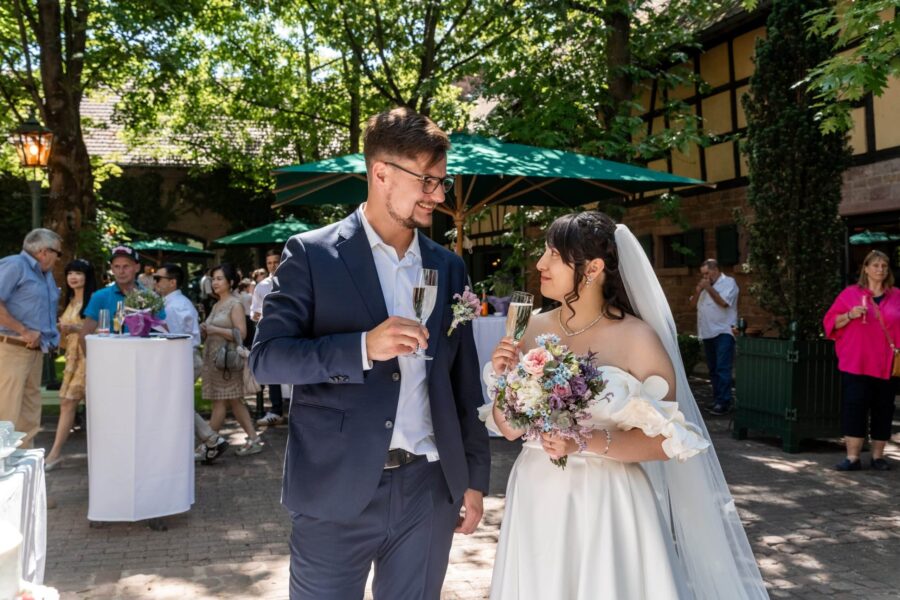 Brautpaar im Garten bei Sekt und Blumenstrauß genießen, Hofgut Hünersdorff