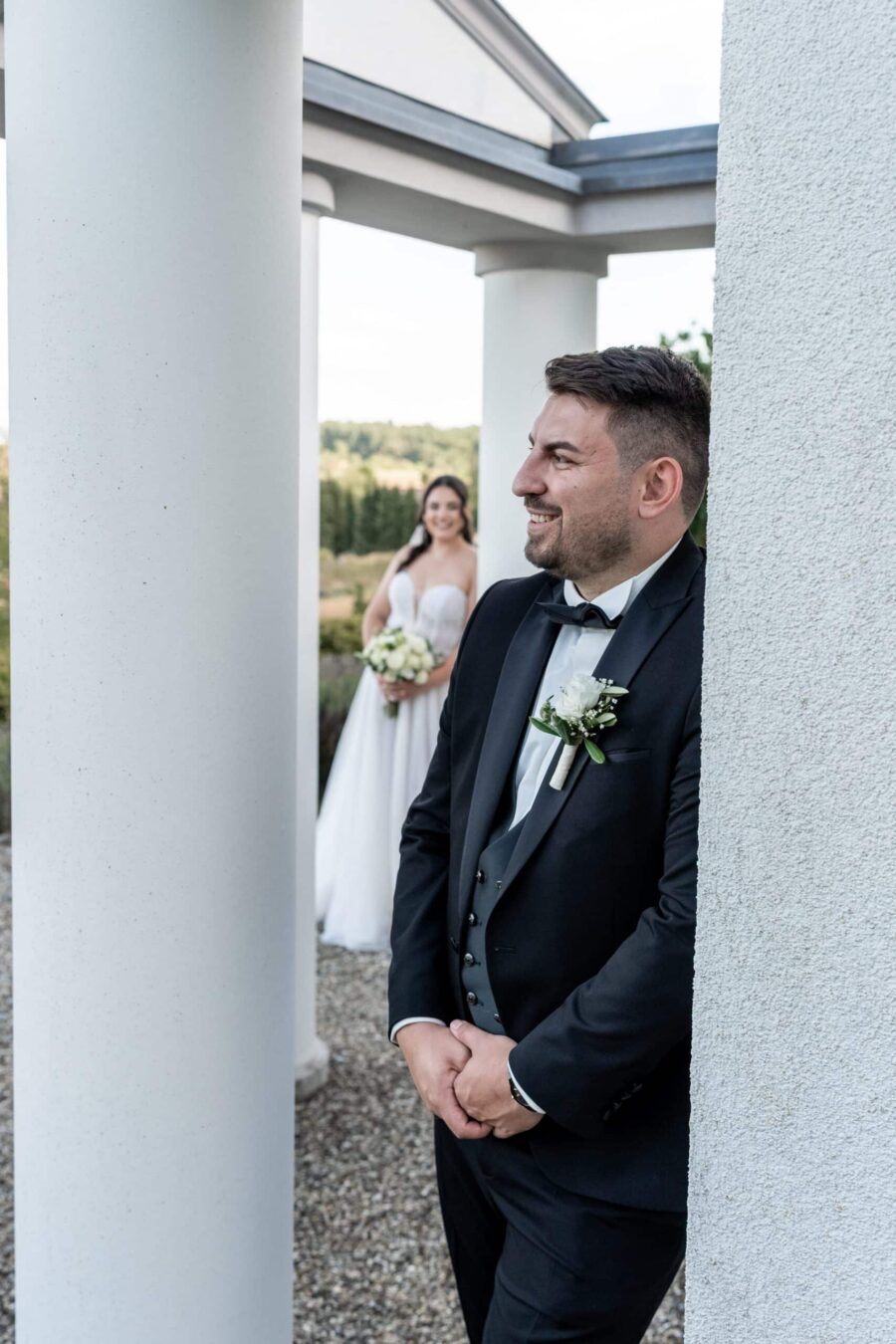 Brautpaar im Garten unter weißem Säulengang