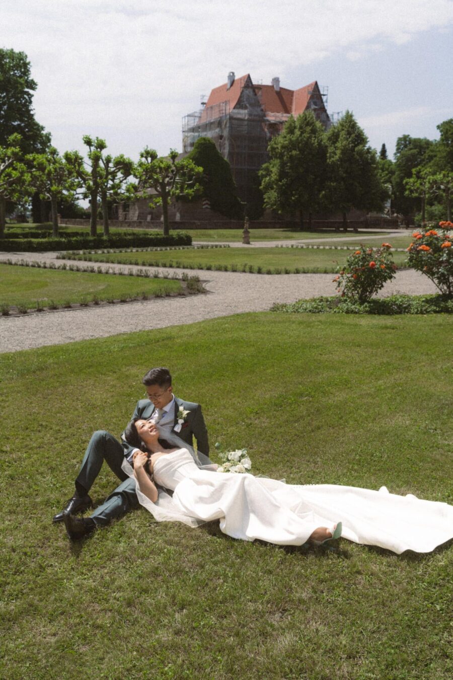 Brautpaar entspannt sich auf Wiese im Garten, Hotel Schindlerhof